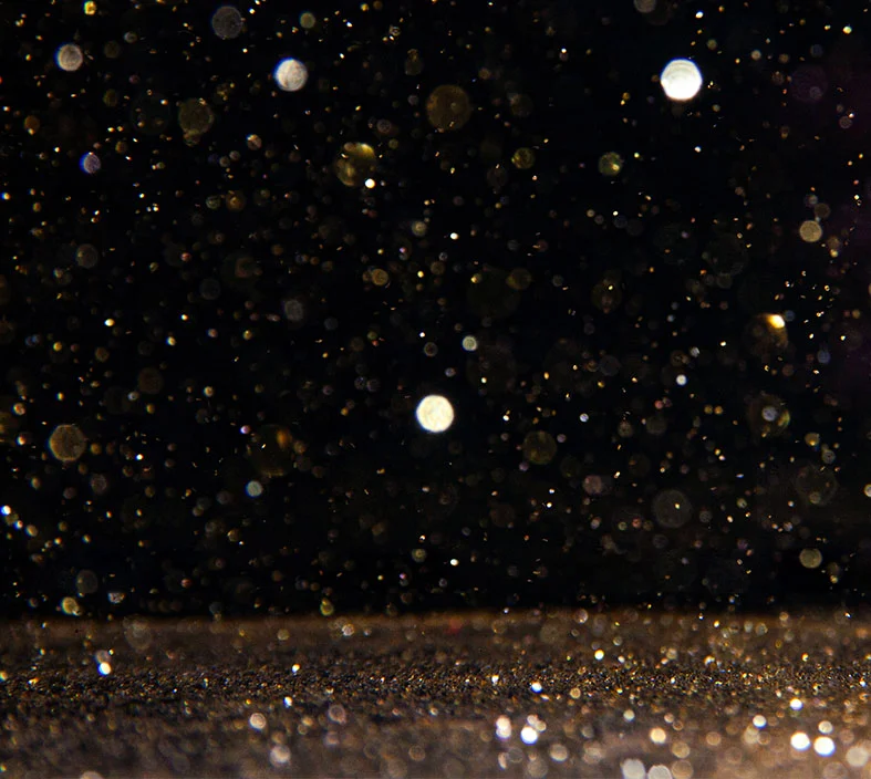 Close-up image of floating dust particles lit against a dark background, symbolizing how dust accumulation reduces solar panel efficiency.