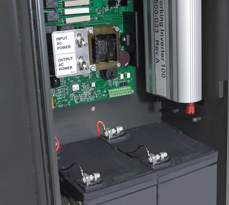 Interior view of the inverter cabinet showing two installed 35 Amp Hour SLA batteries and electronic components.